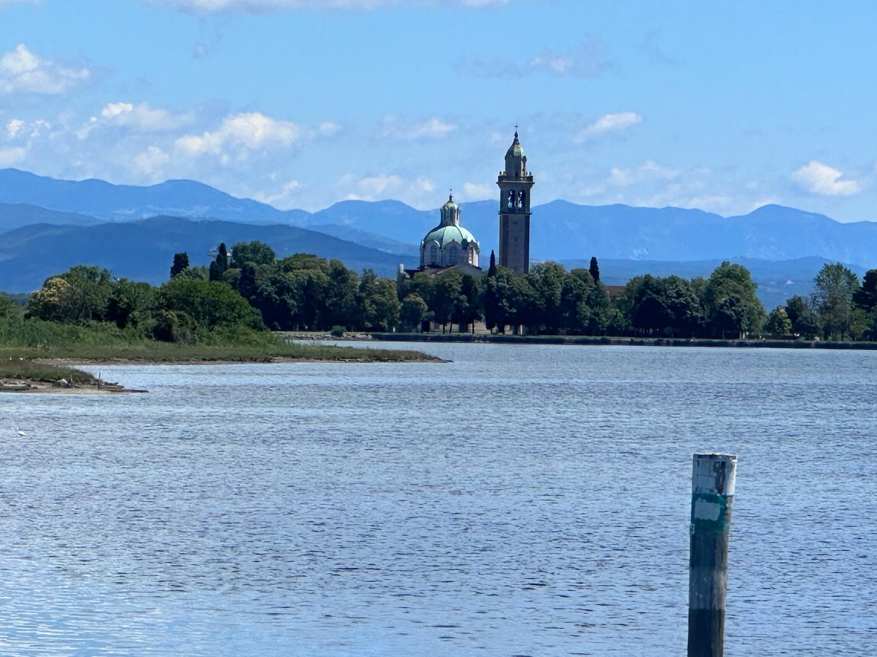 Barbana island sanctuary dome and bell tower before blue mountains