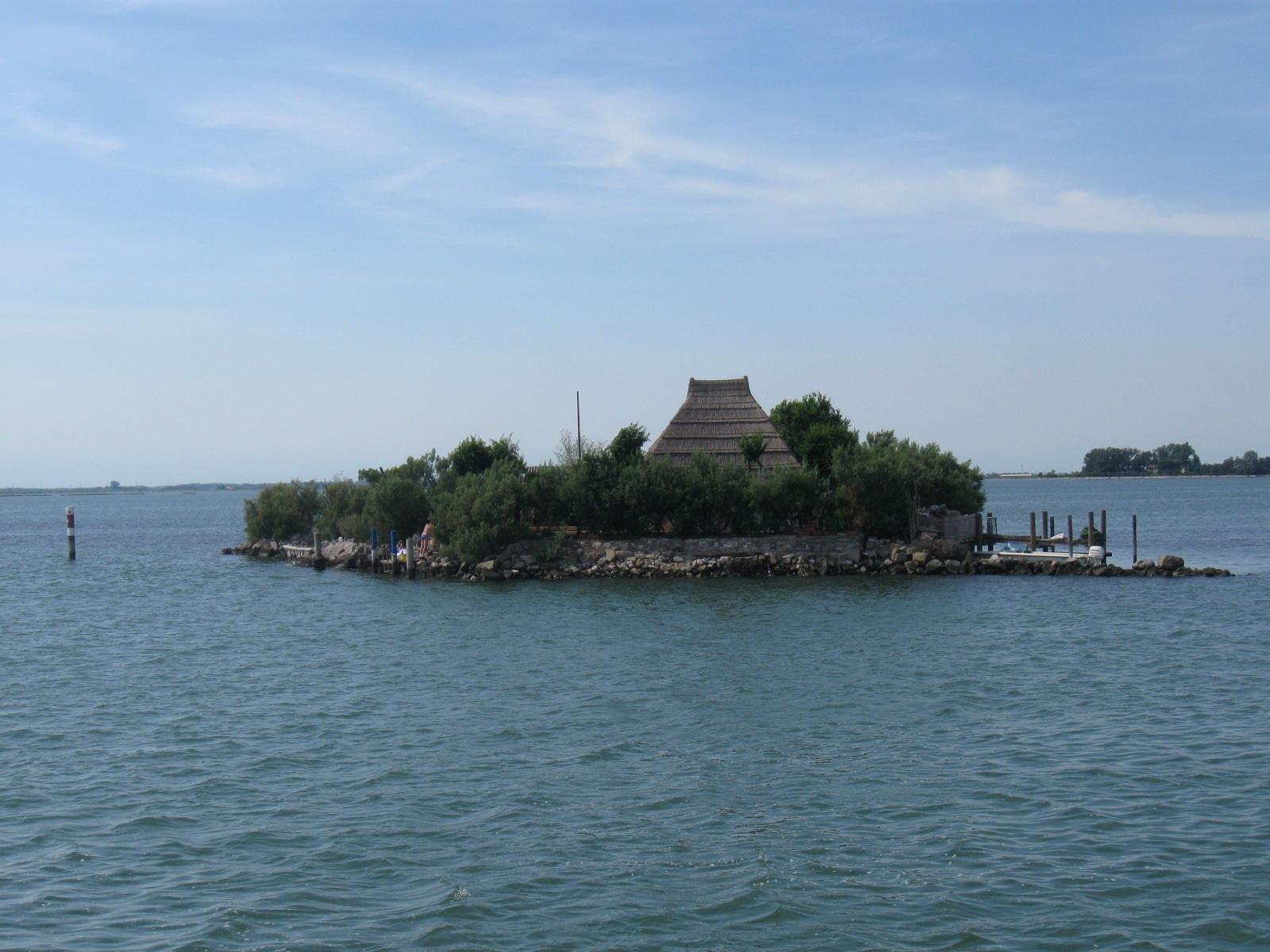 Small lagoon islet with a traditional thatched reed casone hut