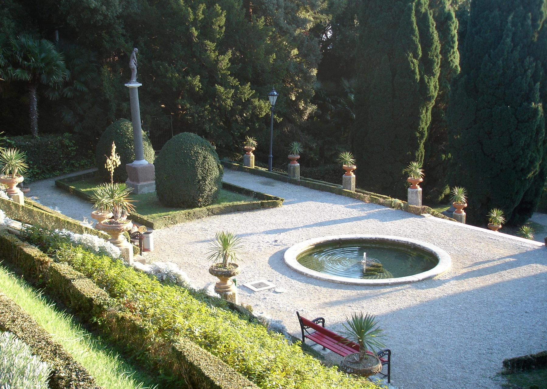 Formal garden with fountain basin and potted palms in Miramare park